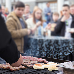 Image showing Beef burgers being grilled on food stall grill.