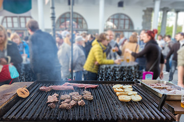 Image showing Beef burgers being grilled on food stall grill.