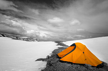 Image showing Orange tent in snow mountains. Selective color.