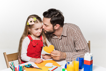 Image showing The daughter and father carving out paper applications 