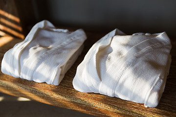 Image showing close up of two white bathrobes on wooden shelf