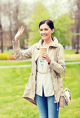 Image showing smiling woman drinking coffee in park