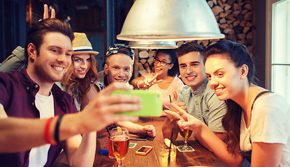 Image showing happy friends with smartphone taking selfie at bar