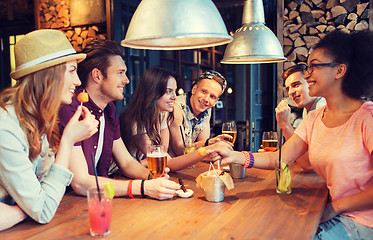 Image showing happy friends with drinks talking at bar or pub