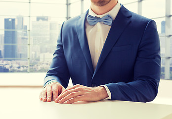 Image showing close up of man in suit and bow-tie at table