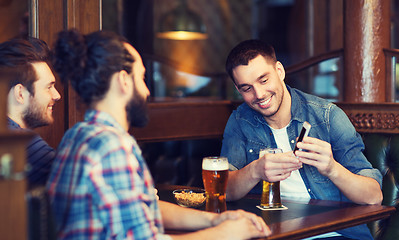 Image showing male friends with smartphone drinking beer at bar