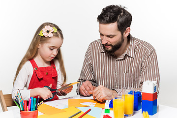 Image showing The daughter and father carving out paper applications 