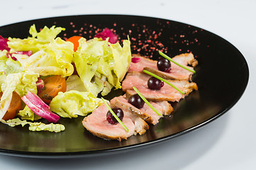 Image showing grilled meat with lettuce. on black plate