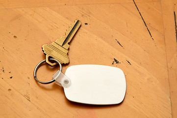 Image showing Keyring with key and white fob on wood table