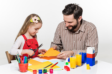 Image showing The daughter and father carving out paper applications 