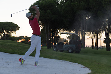 Image showing golfer hitting a sand bunker shot on sunset