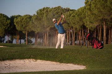 Image showing golfer hitting a sand bunker shot on sunset