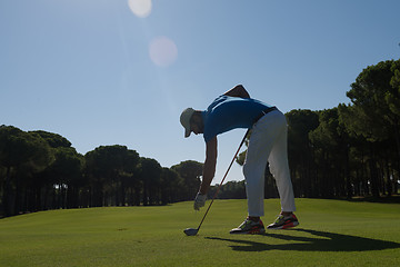 Image showing golf player placing ball on tee