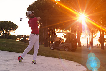 Image showing golfer hitting a sand bunker shot on sunset