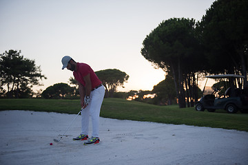 Image showing golfer hitting a sand bunker shot on sunset