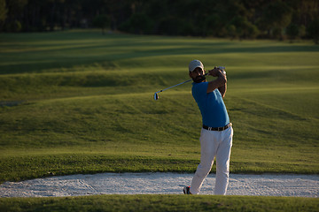 Image showing golfer hitting a sand bunker shot on sunset