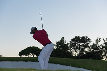 Image showing golfer hitting a sand bunker shot on sunset