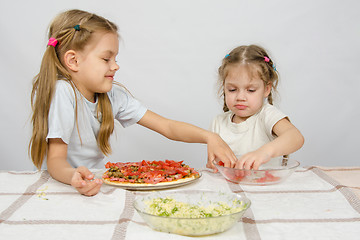 Image showing Two little girls at the table spread on tomato pizza