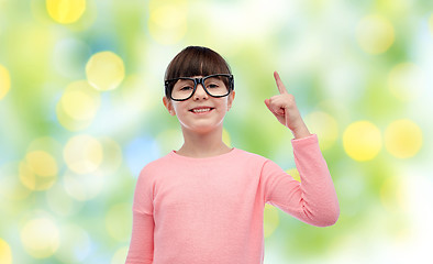 Image showing happy little girl in eyeglasses pointing finger up