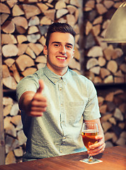 Image showing happy man with beer showing thumbs up at bar