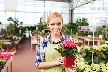 Image showing happy woman holding flowers in greenhouse