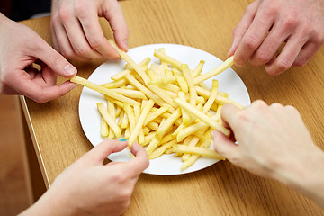 Image showing close up of hands taking french fries from plate