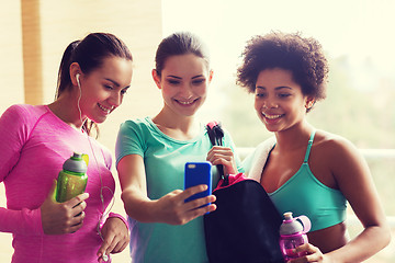 Image showing happy women with bottles and smartphone in gym