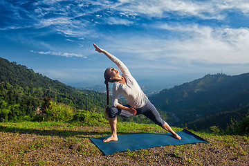 Image showing Woman practices yoga asana Utthita Parsvakonasana outdoors