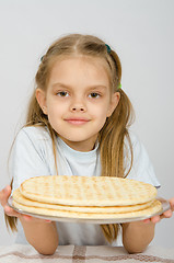 Image showing The girl with a slight smile holding a pizza crust on a plate