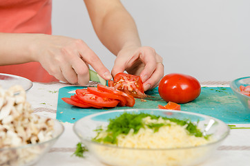 Image showing Close-up of female hands cutting tomato on kitchen table