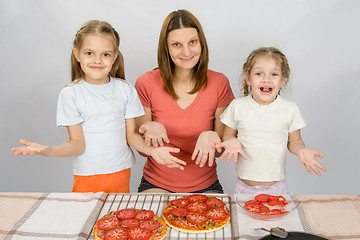 Image showing Mom with two young daughters happily show made pizza with tomatoes