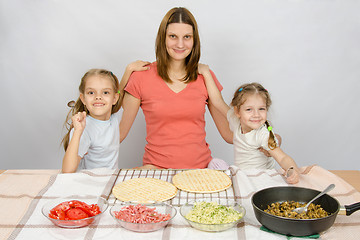 Image showing Mother with two daughters at the kitchen table are going to cook a pizza and a fun look into the frame