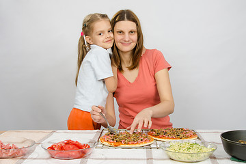 Image showing Daughter hugging her mother, which makes pizza at the table