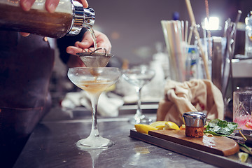 Image showing Bartender coocks cocktail behind a bar counter