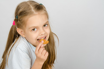 Image showing Portrait of a little six year old girl biting a cookie