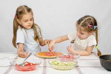 Image showing Six-year girl observes and controls her younger sister puts on the pizza ingredients