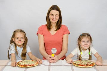 Image showing At the table sat my mother with a knife for pizza and two daughters to whom two pizzas