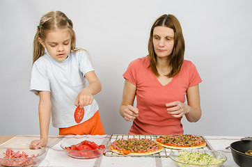 Image showing Six year old girl takes a plate of cutting tomatoes for pizza under the supervision of mum