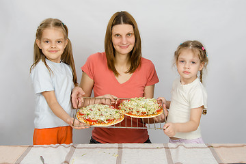 Image showing Mom and two small daughters show the two had not yet made baked pizza on a baking sheet