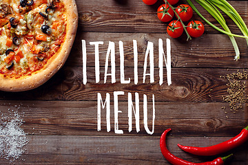 Image showing Italian pizza with tomatoes on a wooden table, top view, close-up