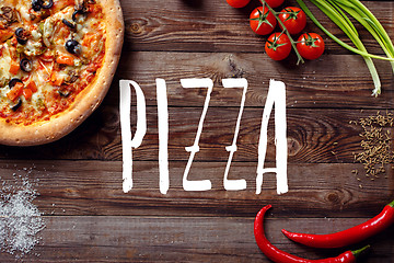 Image showing Italian pizza with tomatoes on a wooden table, top view, close-up. 