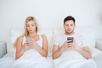 Image showing couple with smartphones in bed