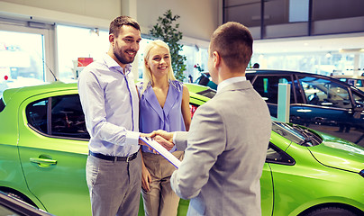 Image showing happy couple with car dealer in auto show or salon