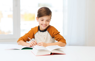 Image showing smiling student boy writing to notebook at home