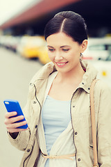 Image showing smiling woman with smartphone over taxi in city