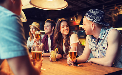 Image showing happy friends with drinks talking at bar or pub