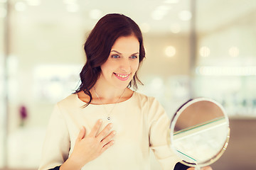 Image showing happy woman choosing pendant at jewelry store