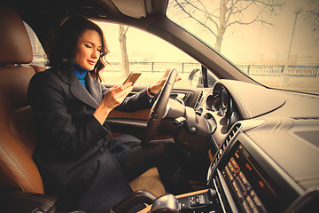 Image showing woman with a smartphone in hand in interior of car