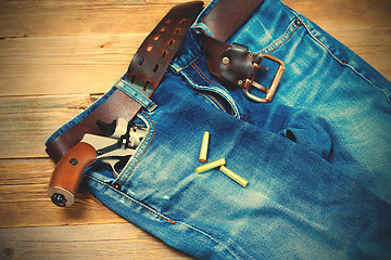 Image showing old blue jeans with silver revolver in his pocket