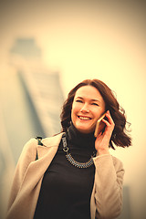 Image showing business woman in a bright coat talking on a cell phone